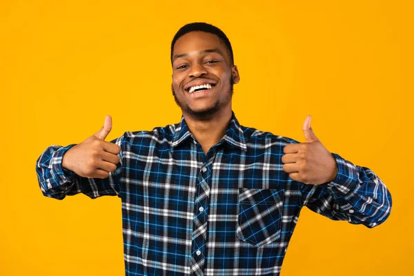 Schwarzer Mann gestikuliert mit beiden Händen Daumen hoch, gelber Hintergrund — Stockfoto