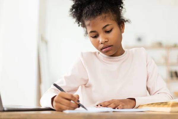 黒人ティーンの女の子は宿題を書いて自宅でお座りを学ぶ — ストック写真