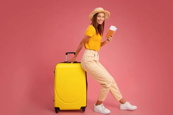 Улыбающаяся молодая женщина в летней одежде опирается на багаж — стоковое фото