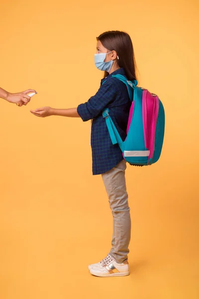 Enfermera usando desinfectante en las manos de las niñas antes de la lección —  Fotos de Stock