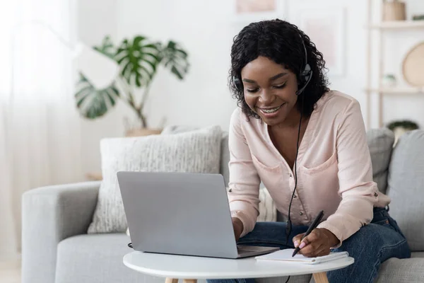 Online onderwijs. Afrikaans meisje met behulp van laptop en headset voor studie thuis — Stockfoto