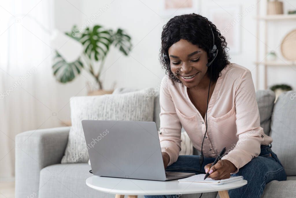 Online Education. African Girl Using Laptop And Headset For Study At Home
