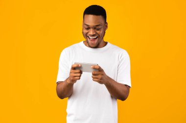Heyecanlı Siyah Adam Akıllı Telefon 'da Oyun Oynuyor, Sarı Arka plan