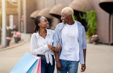 Sınırlı üretim ve büyük indirimler. Alışveriş çantalı neşeli Afrikalı Amerikalı çift.