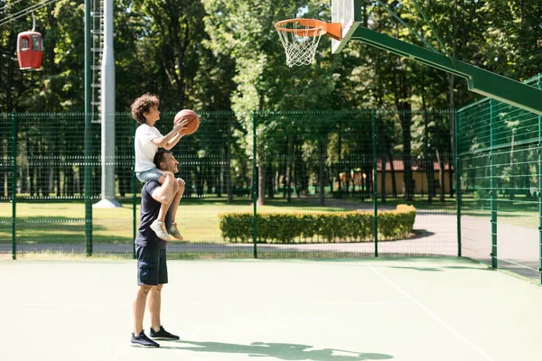 Adam oğlunun basket atmasına yardım ediyor. — Stok fotoğraf