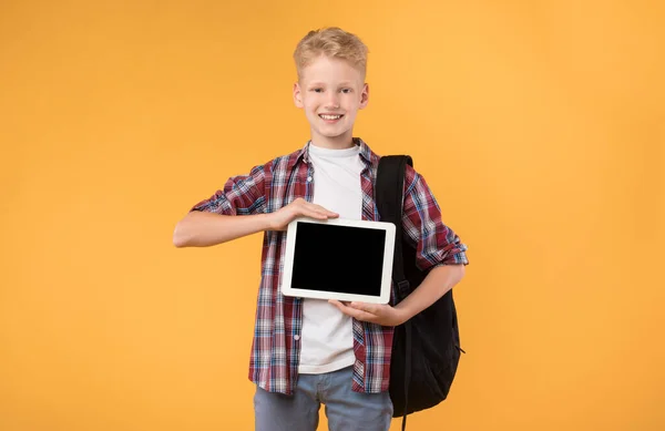 Улыбающийся школьник показывает планшетный экран перед камерой — стоковое фото