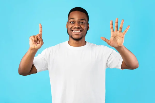 Africano ragazzo conteggio mostra numero sei in piedi oltre blu sfondo — Foto Stock