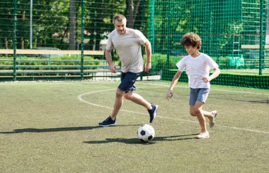 Sportif baba oğluyla futbol oynuyor.