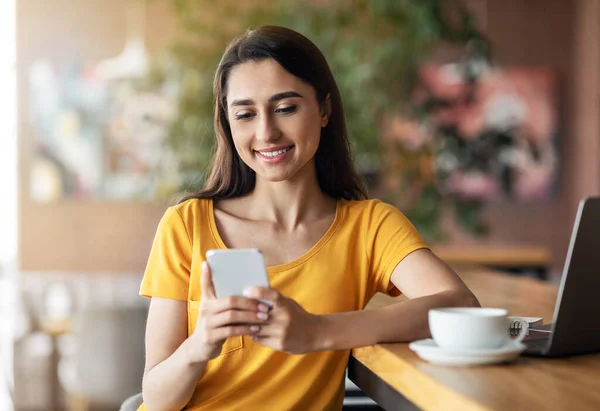 Chica feliz sentado en la cafetería, beber té y el uso de teléfonos inteligentes — Foto de Stock