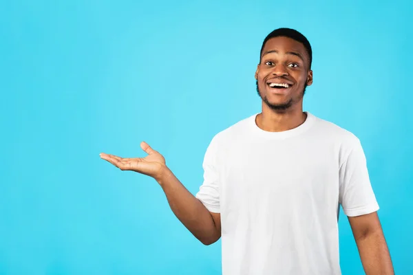Ragazzo afroamericano mostrando spazio libero gesticolando a parte, sfondo blu — Foto Stock