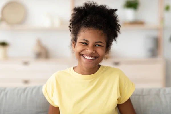 Позитивна чорна дівчина сміється сидячи на дивані вдома — стокове фото