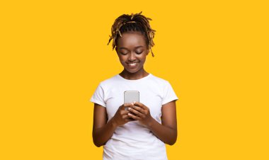 Mutlu siyah kız sarı üzerine cep telefonu kullanıyor.