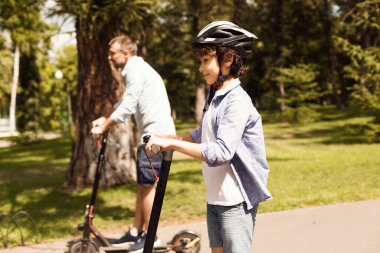 Mutlu bir adam ve babası e-scooter kullanıyor.