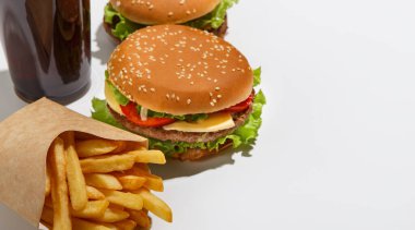 Eve servis ve Amerikan fast food servisi. Çizburger ve hamburger, patates kızartması ve beyaz arka planda izole edilmiş bir bardak kola.