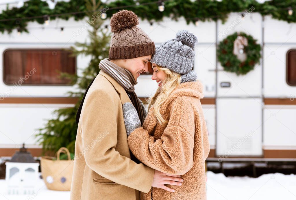 Portrait of happy young couple hugging and laughing outdoors in winter