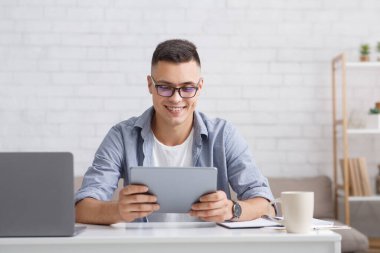 Modern hobiler ve ev için uygulamalar. Bilgisayarlı gülümseyen adam tablete bakıyor.