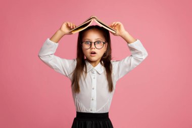 Gözlüklü ilkokul çocuğunun kafasını kitapla örttüğüne şaşırdım.