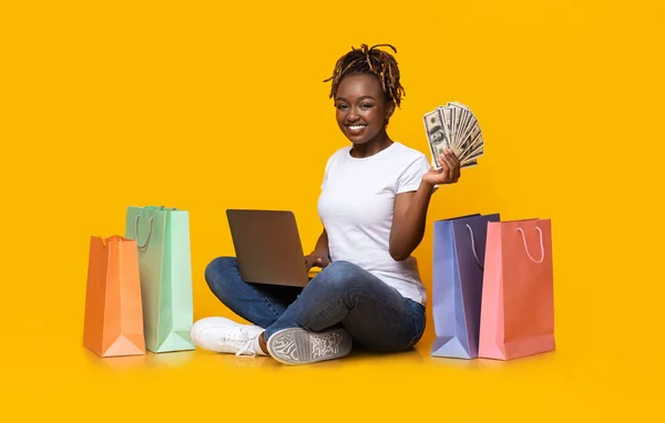 Usmívající se černošky dívka nakupování on-line, pomocí notebooku a hotovosti — Stock fotografie