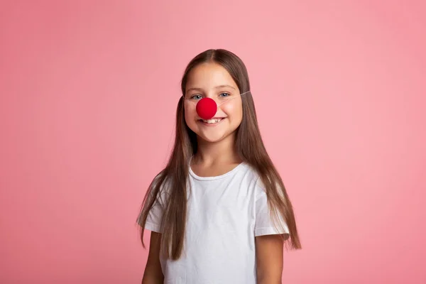 Celebra el cumpleaños. Niña pequeña en camiseta blanca y nariz de payaso rojo — Foto de Stock