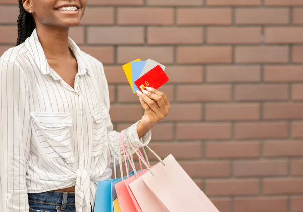 Descuento y tarjetas de crédito para compras. Chica sonriente sosteniendo tarjetas y paquetes en su mano —  Fotos de Stock