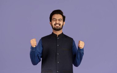 Zafer sahibi Hintli adam EVET hareketi yapıyor, menekşe arka plandaki başarısını kutluyor.