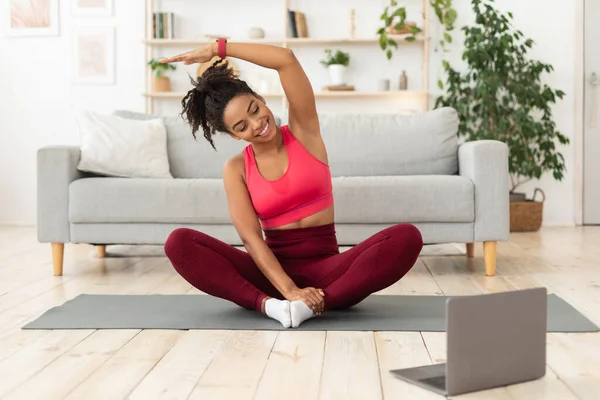 Chica negra haciendo ejercicio en el ordenador portátil tener entrenamiento en línea en casa —  Fotos de Stock