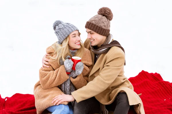 浪漫的情侣们坐在雪地上，喝咖啡 — 图库照片