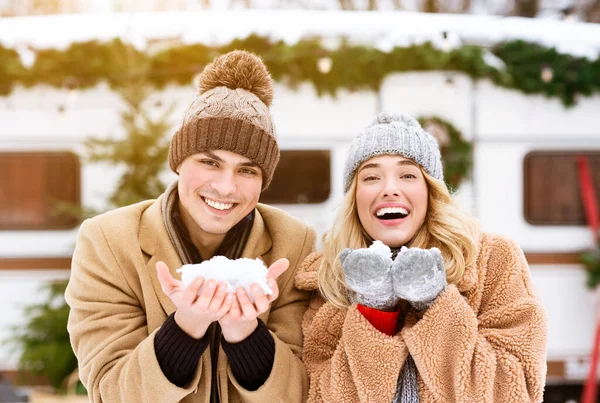 Winterstimmung. Fröhliches junges Paar hält Schnee in den Händen und lächelt in die Kamera — Stockfoto