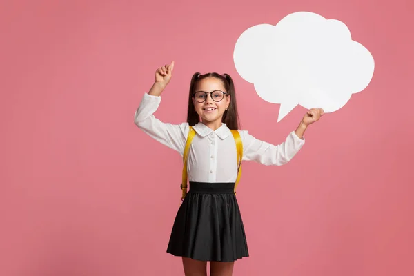Uśmiechnięta dziewczyna w szkolnym mundurze i okularach wskazuje na pustą przestrzeń i posiada abstrakcyjne słowo chmura — Zdjęcie stockowe