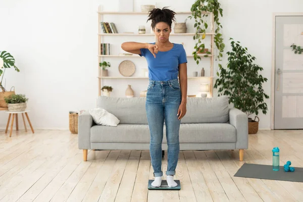 Frustrado menina negra Gesturing polegares para baixo de pé em escalas internas — Fotografia de Stock