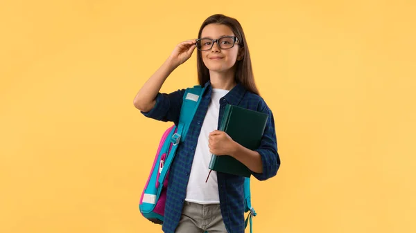 Usmívající se dívka drží učebnici na pozadí studia — Stock fotografie