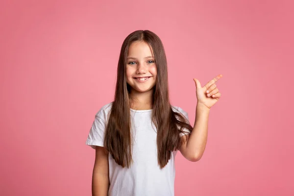 Niño con pelo largo presentando producto. Feliz niña muestra al espacio vacío — Foto de Stock