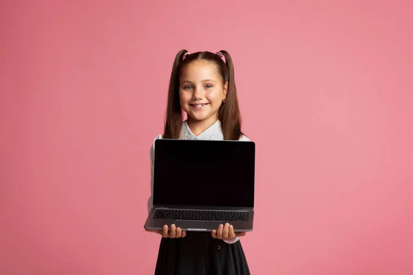 Istruzione remota durante la quarantena. Ragazza sorridente in uniforme scolastica che tiene il computer portatile — Foto Stock