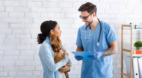 Ετήσιο κτηνιατρικό τσεκάπ. Νεαρός γιατρός μιλάει με τον ιδιοκτήτη του σκύλου στην κλινική ζώων — Φωτογραφία Αρχείου