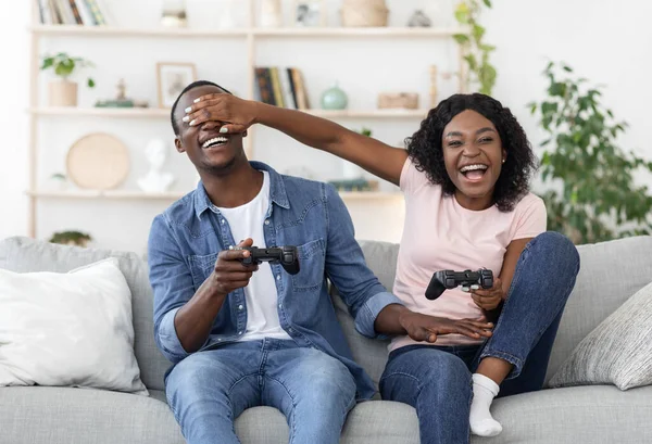 Feliz casal negro jogar vídeo game, mulher cobrindo namorado olhos — Fotografia de Stock