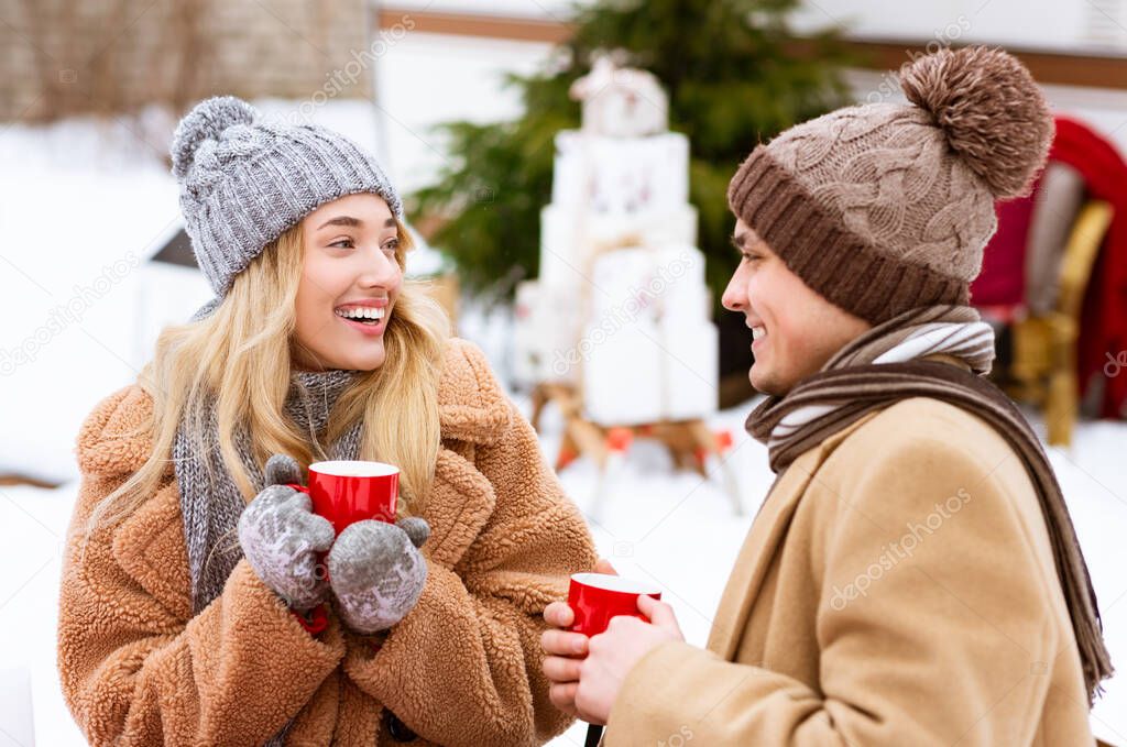 Two Lovers Drinking Hot Tea From Red Mugs During Winter Date Outdoors