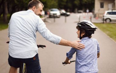 Mutlu babasıyla bisiklete binen çocuğun arka manzarası.