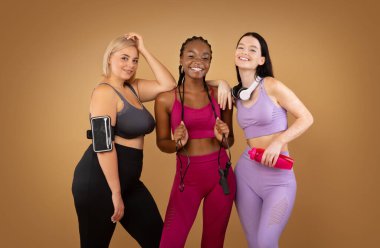 Kahverengi arka planda farklı figür tipli, gülümseyen çok ırklı kadınlar.