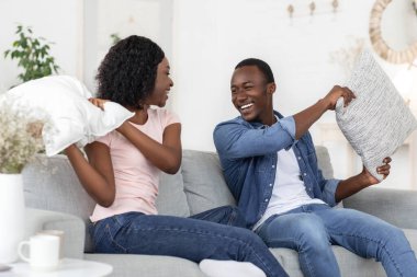 Mutlu, sevecen siyah çift oturma odasında yastıklarla kavga ediyor.