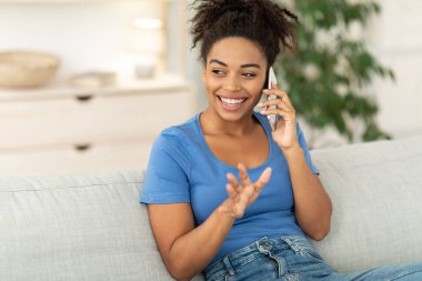Cep telefonuyla konuşan mutlu Afrikalı kadın. İçeride koltukta oturuyor.