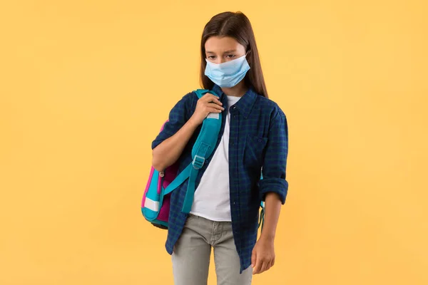 Triste enfant en masque facial isolé sur le mur jaune studio — Photo