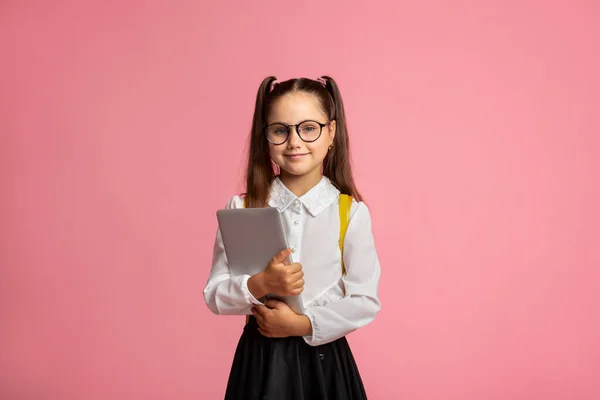 Aplikace do školy. Přátelská školačka v brýlích a uniformě drží tablet — Stock fotografie