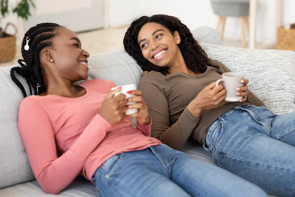 Relaxed girlfriends drinking coffee together at home — Stock Photo, Image