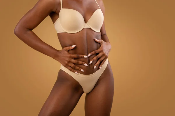 Kahverengi arka planda poz verirken İç Çamaşırlı Siyah Kadın Dokunaklı Göbeğe Sığar — Stok fotoğraf