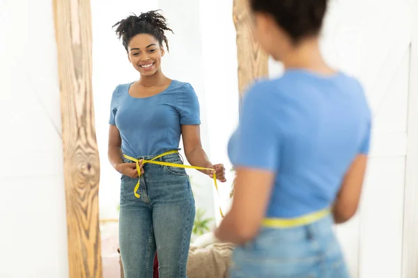 Feliz chica negra después de la pérdida de peso que mide la cintura en casa — Foto de Stock