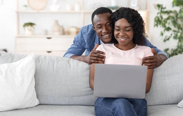 Mooie Afrikaanse vrouw die haar man iets laat zien op de laptop — Stockfoto