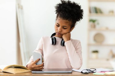 Cep telefonu kullanan Afrikalı Kız Evde Dizüstü bilgisayar başında oturuyor