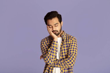 Leylak arkaplanı üzerinde çok çalıştıktan sonra uyuyan yorgun Hintli adam.