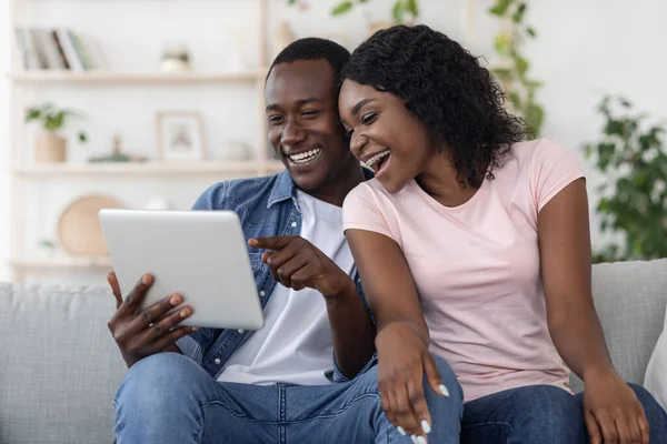 Χαρούμενος μαύρος άνδρας και γυναίκα που χρησιμοποιούν ψηφιακή ταμπλέτα στο σπίτι — Φωτογραφία Αρχείου