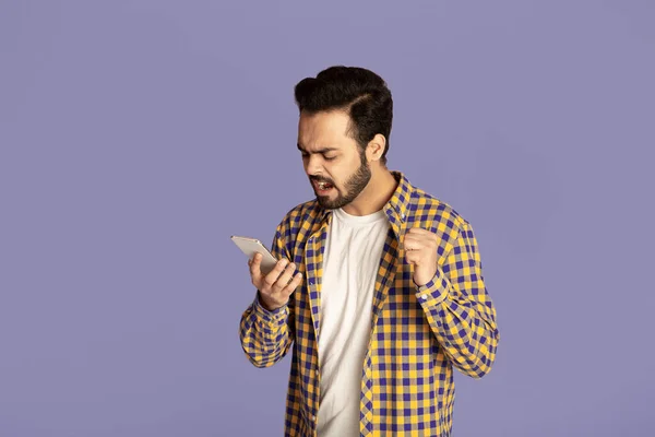 Boze Indiase man schreeuwen op zijn smartphone over lila achtergrond — Stockfoto
